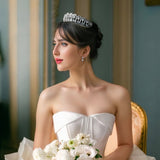  sparkling silver tiara featuring intricate heart-shaped designs and dangling teardrop zirconia stones. The large zirconia stones are suspended to create a dynamic, shimmering effect.